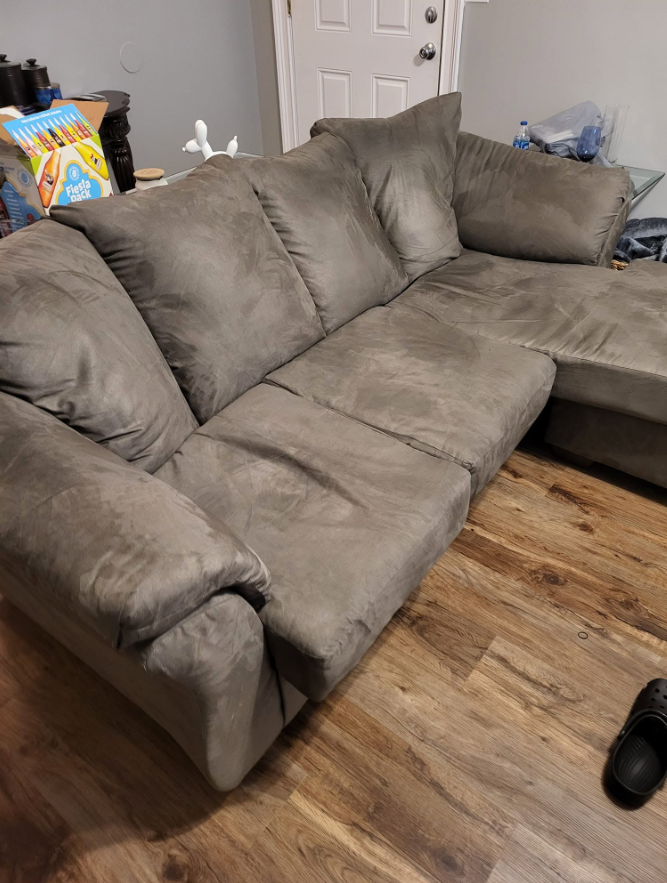 A worn, sagging mass produced sectional in a living room